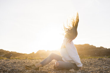 Young woman at the beach, tossing hair at sunset - AFVF00885