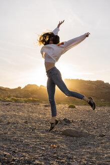 Junge Frau am Strand, tanzend bei Sonnenuntergang - AFVF00887