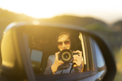 Young woman taking picture of her mirror image in her car stock photo