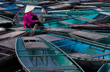 Eine Frau sitzt gedankenverloren inmitten eines Floßes von Booten, Ninh Binh, Vietnam - MINF00905