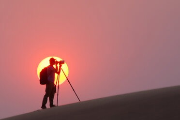 Fotograf im Schatten der untergehenden Sonne in der Namib-Wüste, Namibia - MINF00925