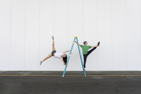 Two acrobats doing tricks on a ladder stock photo