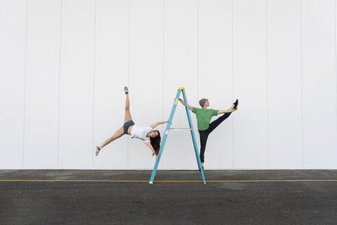 Zwei Akrobaten machen Kunststücke auf einer Leiter - AFVF00895