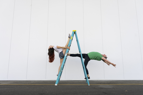 Two acrobats doing tricks on a ladder stock photo