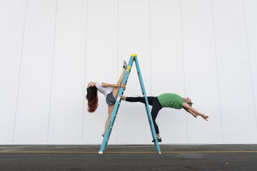Zwei Akrobaten machen Kunststücke auf einer Leiter - AFVF00897