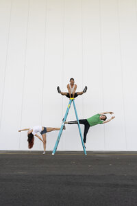 Drei Akrobaten machen Kunststücke auf einer Leiter - AFVF00898