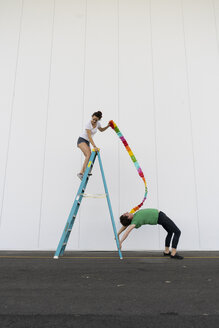 Zwei Akrobaten üben Trick auf einer Leiter mit einem Band - AFVF00900