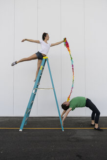 Zwei Akrobaten üben Trick auf einer Leiter mit einem Band - AFVF00901
