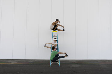 Drei Akrobaten machen Kunststücke auf einer Leiter - AFVF00903