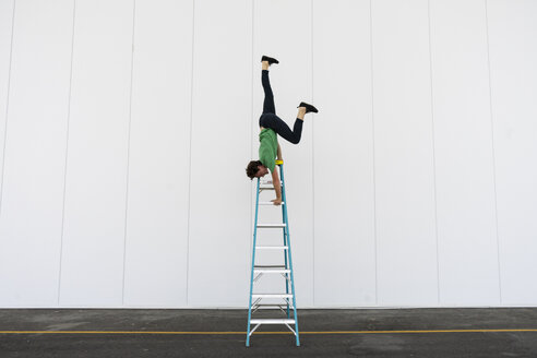 Acrobat balancing upside down on a ladder - AFVF00916