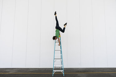 Acrobat balancing upside down on a ladder - AFVF00917