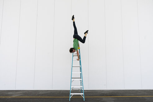 Acrobat balancing upside down on a ladder - AFVF00917
