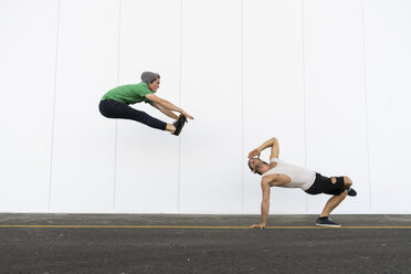 Zwei Akrobaten machen gemeinsam Kunststücke, springen in der Luft - AFVF00926