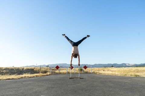 Akrobat im Handstand auf Handstandstöcken, lizenzfreies Stockfoto