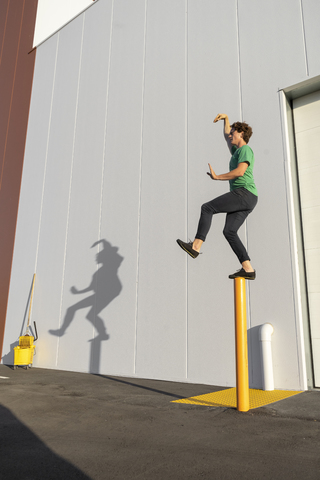 Acrobat standing on pole, casting shadow at cleaning bucket stock photo