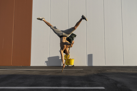 Akrobat spielt mit Putzeimer und Mopp, lizenzfreies Stockfoto