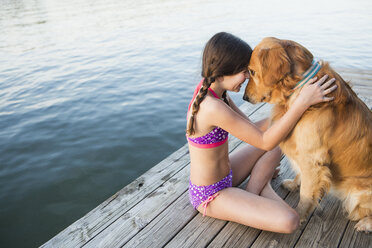 Ein junges Mädchen und ein Golden Retriever Hund sitzen auf einem Steg. - MINF00991