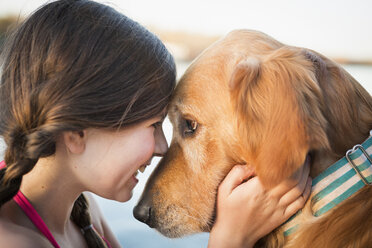 Ein junges Mädchen und ein Golden Retriever Hund, Nase an Nase. - MINF00992