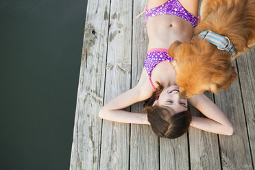 Ein junges Mädchen und ein Golden Retriever Hund auf einem Steg. - MINF00993