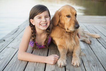Ein junges Mädchen und ein Golden Retriever Hund liegen auf einem Steg. - MINF00995