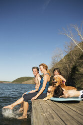 Eine Familie und ihr Retriever-Hund auf einem Steg an einem See. - MINF00997