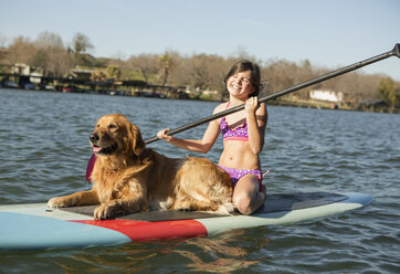 Ein Kind und ein Retriever-Hund auf einem Paddleboard auf dem Wasser. - MINF00999