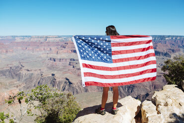 USA, Arizona, Rückenansicht einer Frau mit amerikanischer Flagge, die den Blick auf den Grand Canyon National Park genießt - GEMF02172