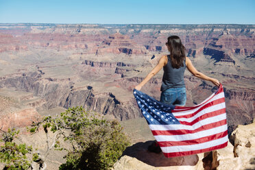 USA, Arizona, Rückenansicht einer Frau mit amerikanischer Flagge, die den Blick auf den Grand Canyon National Park genießt - GEMF02173