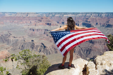 USA, Arizona, Rückenansicht einer Frau mit amerikanischer Flagge, die den Blick auf den Grand Canyon National Park genießt - GEMF02174