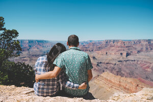 USA, Arizona, Grand Canyon National Park, Rückenansicht eines Paares, das nebeneinander sitzt und die Aussicht betrachtet - GEMF02197