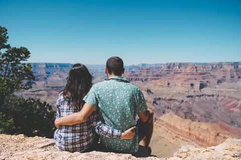 USA, Arizona, Grand Canyon National Park, Rückenansicht eines Paares, das nebeneinander sitzt und die Aussicht betrachtet, lizenzfreies Stockfoto