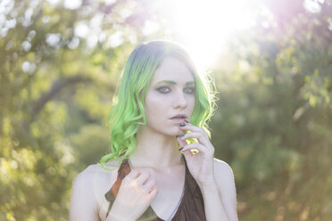Porträt einer jungen Frau mit grün gefärbtem Haar und Augenbrauen im Gegenlicht - AFVF01000
