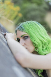 Porträt einer jungen Frau mit grün gefärbten Haaren und Augenbrauen in der Natur - AFVF01006