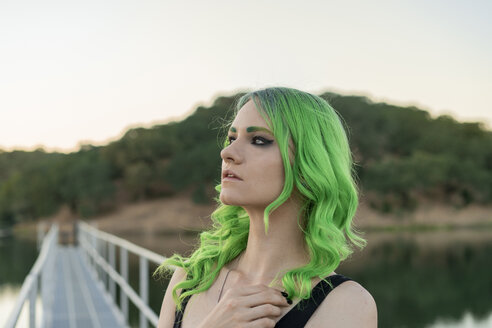 Porträt einer jungen Frau mit grün gefärbten Haaren und Augenbrauen in der Natur - AFVF01009