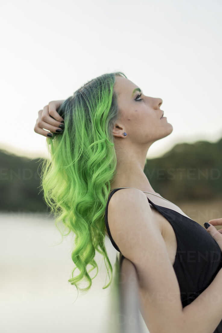 Profil einer jungen Frau mit gefärbten grünen Haaren und Augenbrauen in der  Natur, lizenzfreies Stockfoto