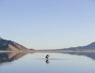 Mann, der durch die weiten und überfluteten Bonneville Salt Flats, Utah, läuft - MINF01061