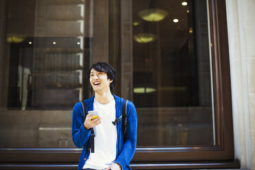 Junger Japaner, der einen Tag in London genießt und ein Smartphone benutzt. - MINF01075