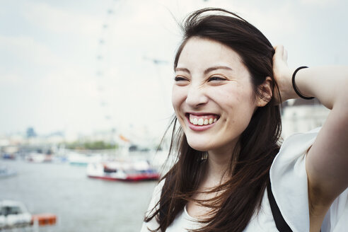 Junge Japaner, die einen Tag in London genießen, stehen an der Themse, im Hintergrund das London Eye. - MINF01085