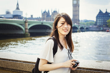 Young Japanese woman enjoying a day out in London, standing on the Queen's Walk by the River Thames. - MINF01087