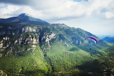 A paraglider in flight over a valley in the mountains. - MINF01127