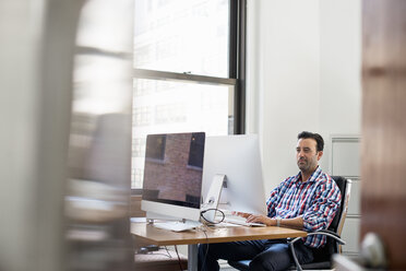 A man working in an office at a desk using a computer. - MINF01143