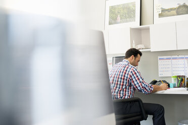 Ein Mann arbeitet in einem Büro an einem Schreibtisch mit einem Computer. - MINF01146