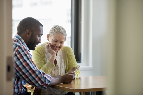 A man and woman in an office, sharing a digital tablet. - MINF01151