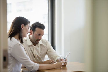 A man and woman in an office, sharing a digital tablet. - MINF01152