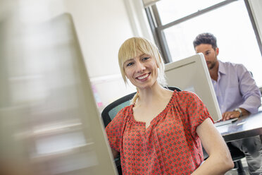 Büroalltag: Zwei Personen, die an Schreibtischen sitzen und Computer benutzen. - MINF01163