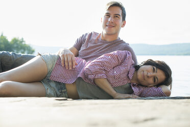 A couple relaxing, lying on a wooden jetty by a lake in summer. - MINF01249