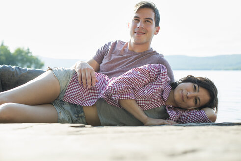Ein Paar, das sich im Sommer auf einem Holzsteg an einem See entspannt. - MINF01249