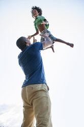 A man lifting a small boy up above his head in play. - MINF01254
