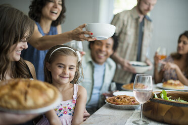 Eine Familie, die sich zum Essen trifft: Erwachsene und Kinder an einem Tisch. - MINF01261