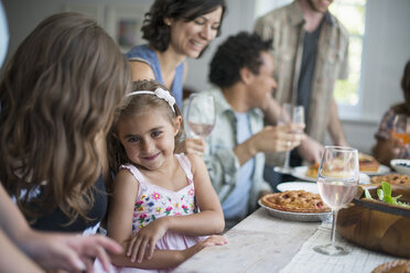 Eine Familie, die sich zum Essen trifft: Erwachsene und Kinder an einem Tisch. - MINF01262